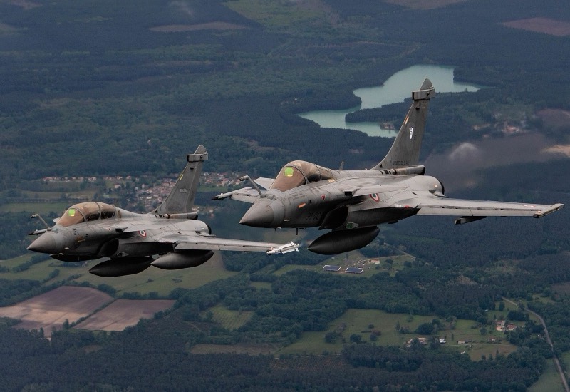 Deux Rafale gris de l’armée de l’Air française en vol au-dessus d’une campagne verte
